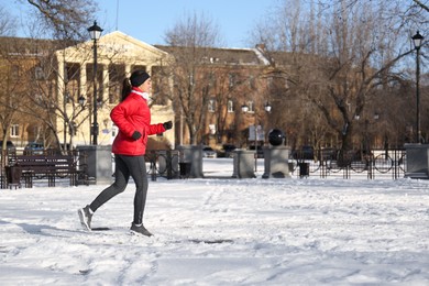 Happy woman running along park on winter day. Outdoors sports exercises