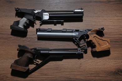 Photo of Different pistols on wooden table. Gun shooting sport
