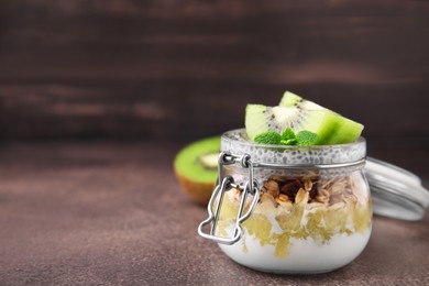 Photo of Delicious dessert with kiwi and chia seeds on brown table, closeup. Space for text