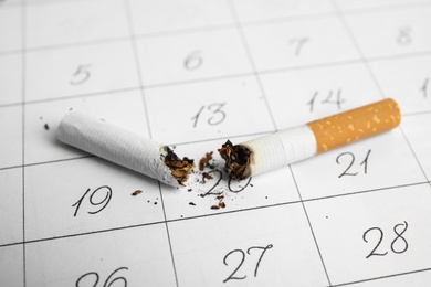 Cigarette stubs on calendar sheet, closeup. Quitting smoking concept