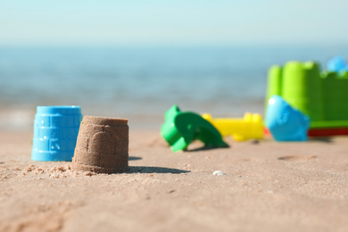 Different child plastic toys and sand castle on beach. Space for text