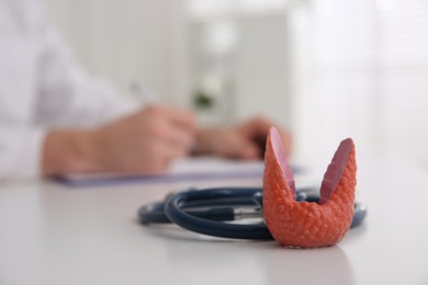 Thyroid gland model and stethoscope on table indoors. Space for text