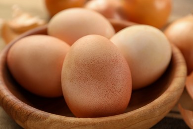 Photo of Easter eggs painted with natural dye in wooden bowl, closeup