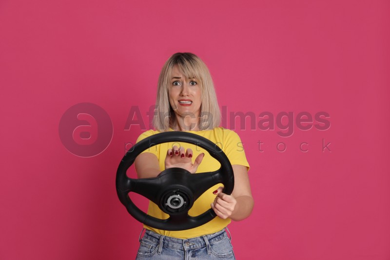 Emotional woman with steering wheel on crimson background