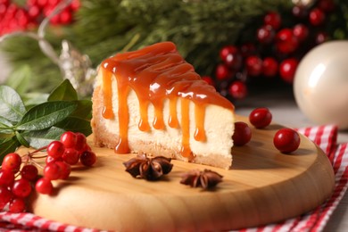 Photo of Tasty caramel cheesecake and Christmas decorations on table, closeup