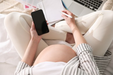 Pregnant woman working on bed at home, above view. Maternity leave