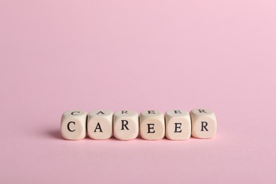 Photo of Stone cubes with word CAREER on pink background. Space for text
