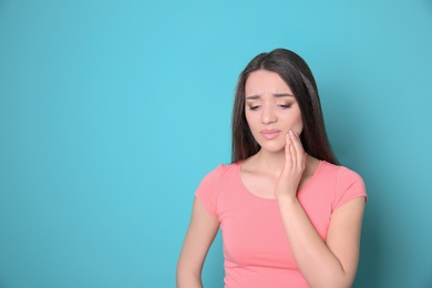 Woman with sensitive teeth on color background