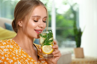 Young woman with glass of lemonade at home. Refreshing drink