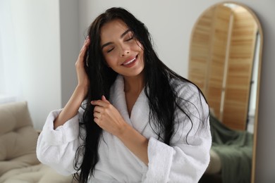 Beautiful young woman wearing white bathrobe indoors