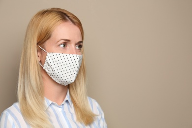 Woman wearing handmade cloth mask on beige background, space for text. Personal protective equipment during COVID-19 pandemic