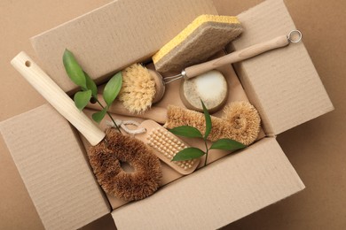 Photo of Cardboard box with eco friendly products on craft paper, top view