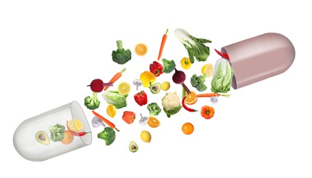 Dietary supplements. Capsule and different fresh vegetables and fruits flying on white background