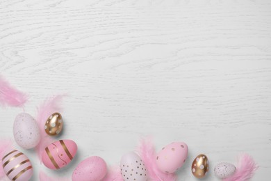 Photo of Flat lay composition with festively decorated Easter eggs on white wooden table. Space for text