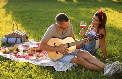 Happy couple with guitar on picnic in park