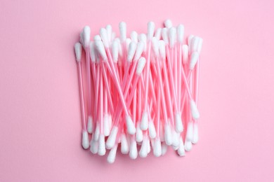 Heap of cotton buds on pink background, top view