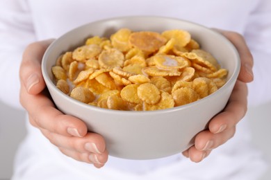 Woman holding bowl of crispy corn flakes with milk, closeup