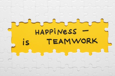 Photo of Recruitment concept. Phrase Happiness Is Teamwork surrounded by assembled white jigsaw puzzle pieces, top view