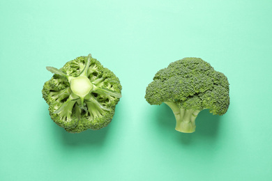 Fresh tasty broccoli on turquoise background, flat lay