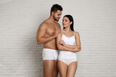 Young couple in white underwear near brick wall