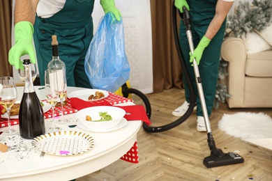 Cleaning service team working in messy room after New Year party, closeup