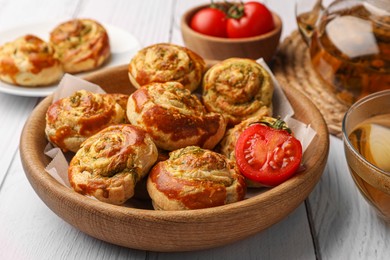 Photo of Fresh delicious puff pastry with tasty filling and tomato in bowl on white wooden table, closeup