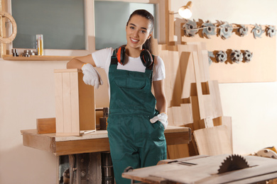 Professional female carpenter in uniform near workbench