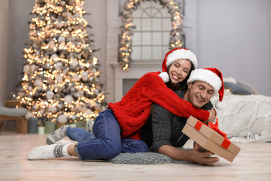 Young woman presenting Christmas gift to her boyfriend at home