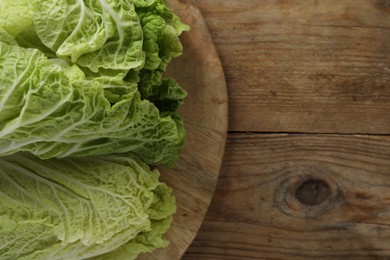 Photo of Fresh ripe leaves of Chinese cabbage on wooden table, top view. Space for text