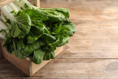 Fresh green pak choy cabbages in crate on wooden table, closeup. Space for text