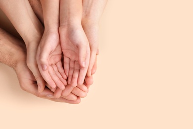 Top view of parents and kid holding empty hands together on beige background, space for text. Family day