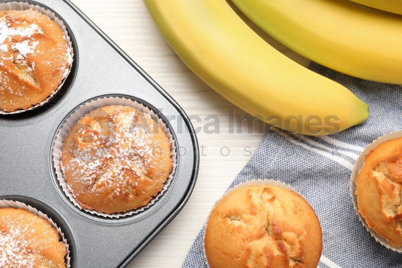 Flat lay composition with tasty banana muffins on white wooden table