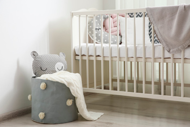 Basket with toy near crib in baby room. Interior design