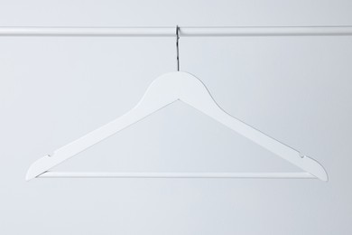 White clothes hanger on metal rail against light background