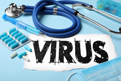 Word VIRUS, stethoscope and medicines on light blue background, closeup
