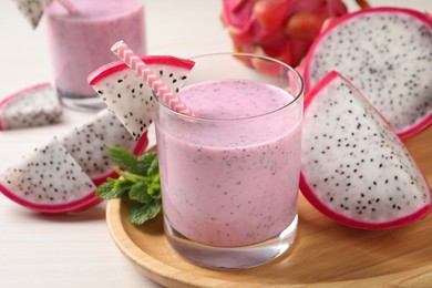 Delicious pitahaya smoothie, mint and fresh fruits on white wooden table, closeup