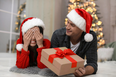 Man presenting Christmas gift to his girlfriend at home