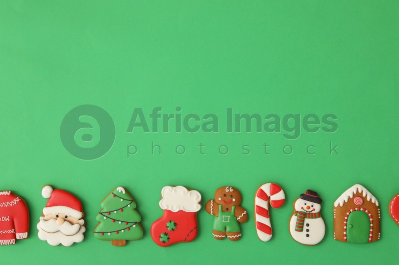 Different Christmas gingerbread cookies on green background, flat lay. Space for text