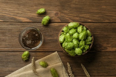 Glass of beer, fresh green hops and spikes on wooden table, flat lay