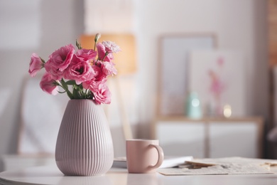 Vase with beautiful eustoma flowers on table in modern room interior, space for text