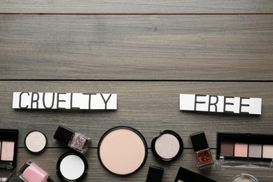 Flat lay composition with words Cruelty Free and different cosmetic products not tested on animals against wooden background. Space for text