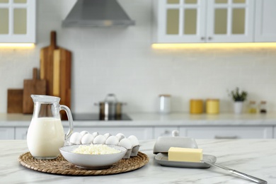 Different dairy products and eggs on white table in modern kitchen. Space for text