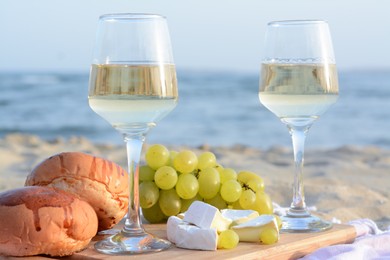 Glasses with white wine and snacks for beach picnic on sandy seashore