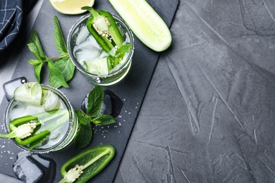 Spicy cocktail with jalapeno, cucumber and lime on black table, flat lay. Space for text