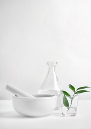 Composition with mortar and pestle on table against light background. Homemade cosmetic products