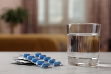 Photo of Glass of water, condoms and pills on white table indoors, space for text. Potency problem concept