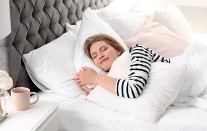 Young woman embracing pillow while sleeping in bed at home