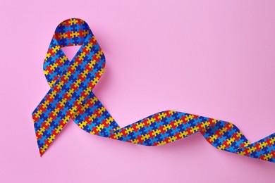 World Autism Awareness Day. Colorful puzzle ribbon on pink background, top view