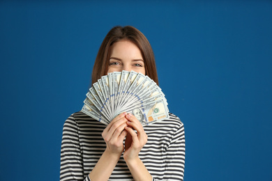 Young woman with cash money on blue background