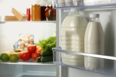 Gallon and bottle of milk in refrigerator, closeup. Space for text